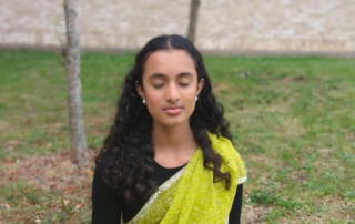 Girl standing outdoors with her eyes shut in meditation